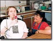 A mobile arm support — also known as a forearm orthosis — allows Jason to eat and drink independently, while physical therapist Lee Winemiller observes.